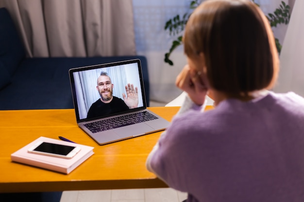 Bezpłatne zdjęcie kobieta w domu rozmowa wideo twarzą w twarz z jej przyjacielem mężem chłopakiem, rozmawiając online z laptopa