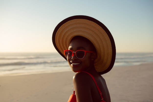 Kobieta w kapeluszu i okularach przeciwsłonecznych relaksuje na plaży