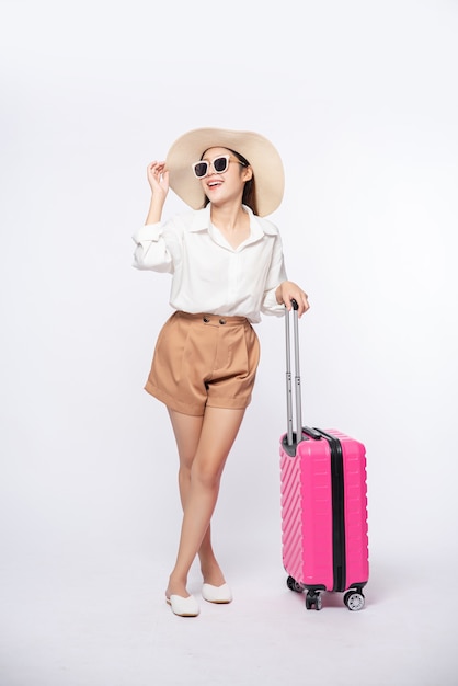 Kobieta w kapeluszu, okularach i uchwytach walizek do podróży