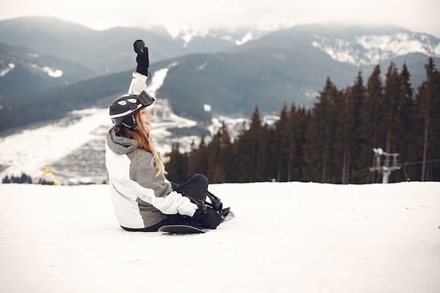Kobieta w kombinezonie snowboardowym. Sportsmenka na górze ze snowboardem w rękach na horyzoncie. Koncepcja sportu