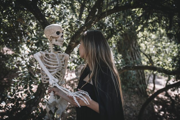 Kobieta w kostium czarownicy gospodarstwa przerażający szkielet