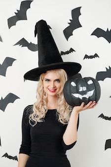 Kobieta w kostiumie na halloween pokazująca czarną bani
