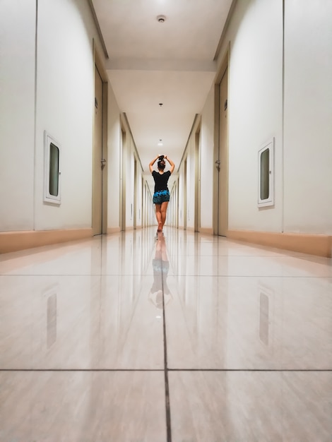 Bezpłatne zdjęcie kobieta w krótkich spodenkach spacerująca w wąskim nowoczesnym korytarzu