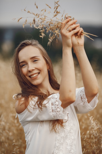 Kobieta w letnim polu. Brunetka w białej sukni.