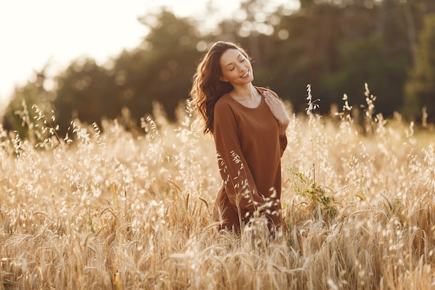 Kobieta w letnim polu. Brunetka w brązowym swetrze.