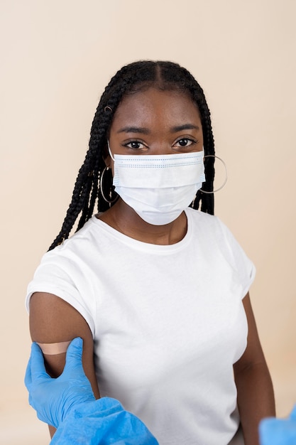 Kobieta w masce medycznej otrzymująca naklejkę na ramieniu po otrzymaniu szczepionki