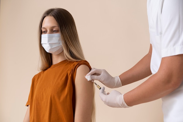 Kobieta w masce medycznej otrzymująca szczepionkę