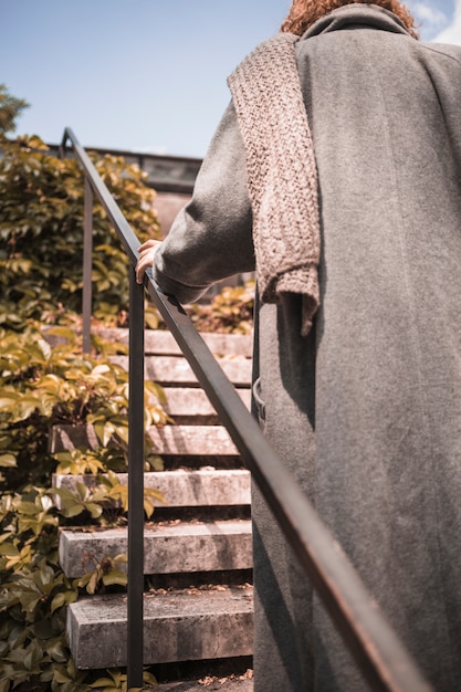 Kobieta w płaszczu skalowanie na schodach