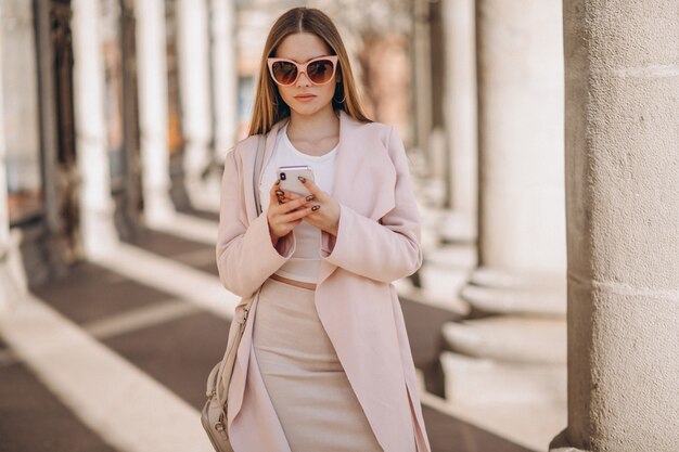 Kobieta w płaszczu spaceru na ulicy i rozmawia przez telefon
