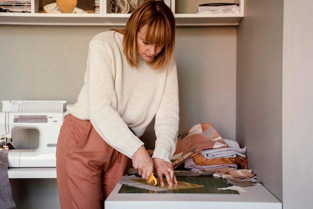 Bezpłatne zdjęcie kobieta w pomieszczeniu pracuje z tkaniną na ubrania