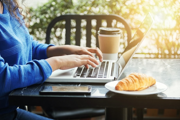 Kobieta w restauracji z jej laptopa i filiżankę kawy