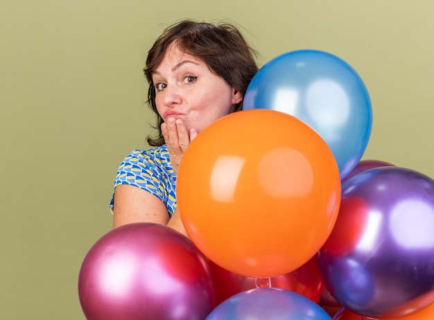 Kobieta w średnim wieku kilka kolorowych balonów z uśmiechem na szczęśliwej twarzy