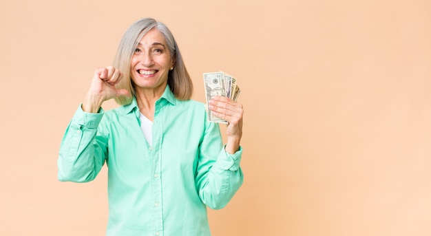 Kobieta w średnim wieku z banknotów dolara na ścianie przestrzeni kopii