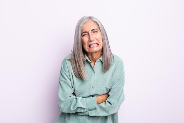 Kobieta w średnim wieku z siwymi włosami czuje się niespokojna, chora, chora i nieszczęśliwa, cierpi na bolesny ból brzucha lub grypę