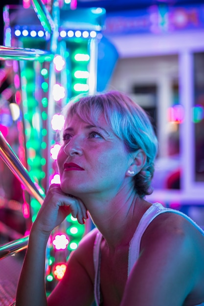 Kobieta w średnim wieku zastanawia się nad świecącymi lampami