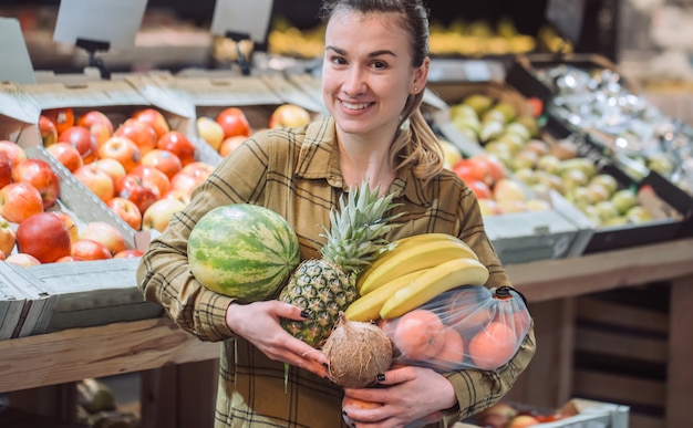 Kobieta w supermarkecie. Piękna młoda kobieta robi zakupy w supermarkecie i kupuje świeżych organicznie warzywa