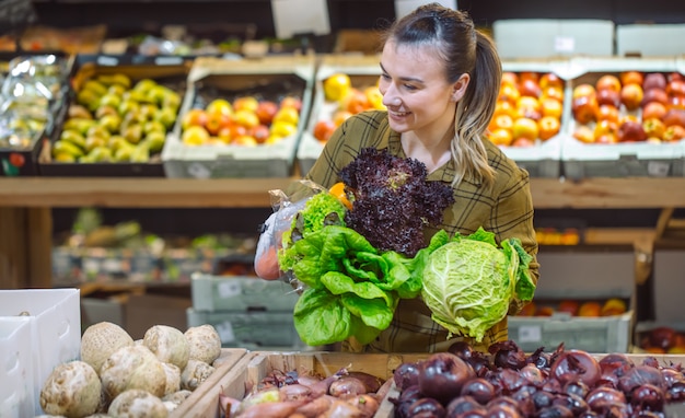 Kobieta w supermarkecie. Piękna młoda kobieta zakupy w supermarkecie i kupowanie świeżych organicznych warzyw