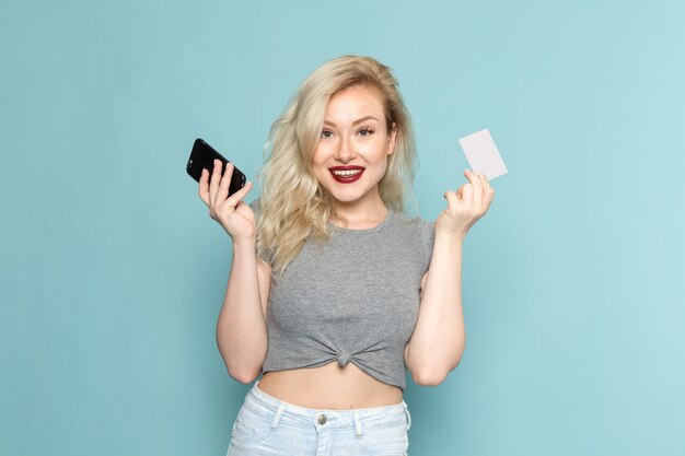 kobieta w szarej koszuli i jasnych niebieskich dżinsach trzymając telefon i białą kartę