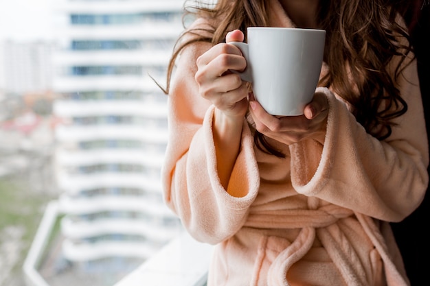 Kobieta w szlafroku trzymając kubek gorącej herbaty. Jesienny nastrój.