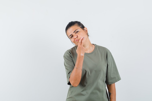 kobieta w t-shirt, trzymając rękę na brodzie i patrząc zamyślony