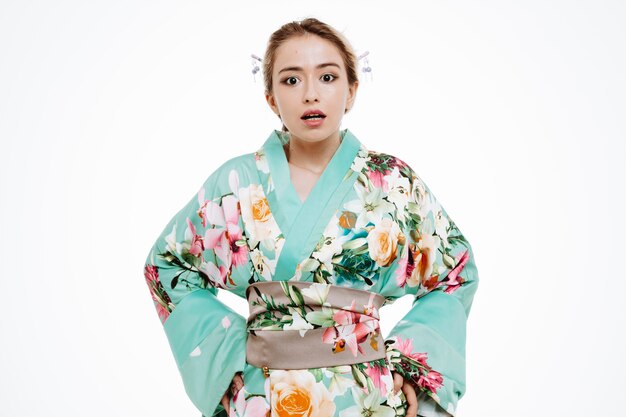 Kobieta w tradycyjnym japońskim kimonie wygląda na zdezorientowaną i zaskoczoną na białym tle