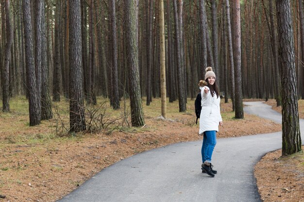 Kobieta wskazuje przy kamerą na lasowej ścieżce