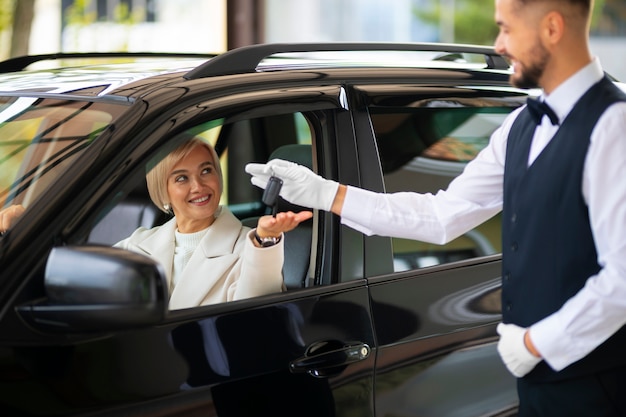 Bezpłatne zdjęcie kobieta wymieniająca kluczyki do samochodu z parkingowym