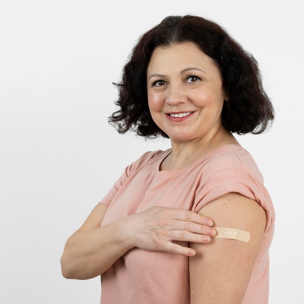Bezpłatne zdjęcie kobieta z bandażem na ramieniu po szczepieniu