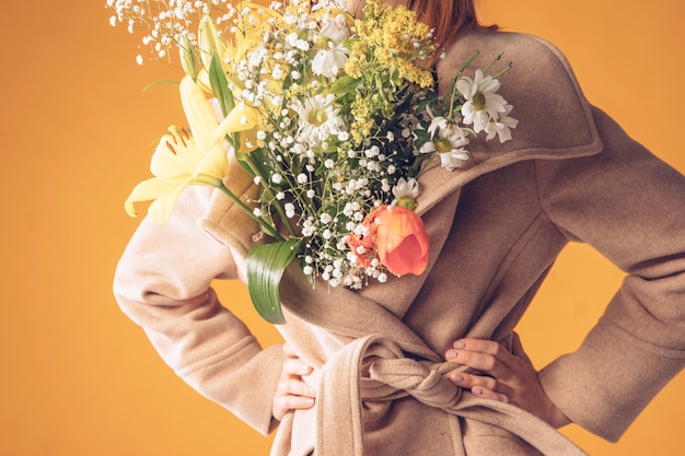 Bezpłatne zdjęcie kobieta z bukietem kwiatów w płaszczu