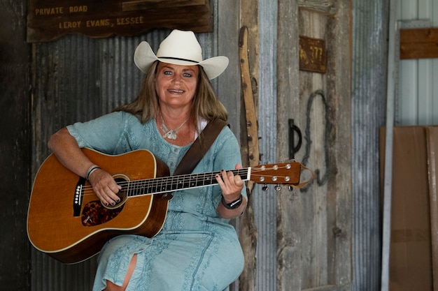 Bezpłatne zdjęcie kobieta z gitarą przygotowuje się do koncertu muzyki country