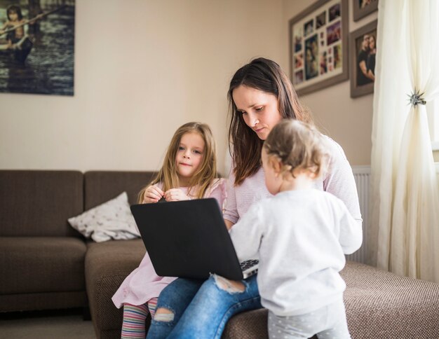 Kobieta z jej dziećmi używa laptop