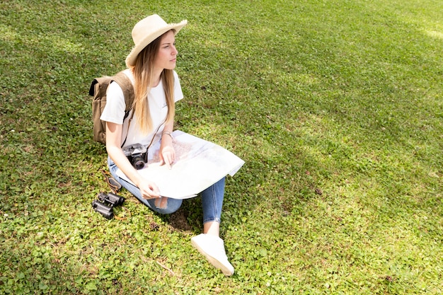 Kobieta z kapeluszowym obsiadaniem na trawie i patrzeć daleko od