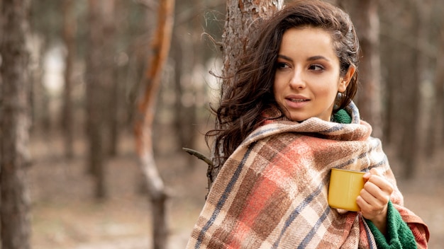 Kobieta z koc i herbacianą filiżanką w naturze