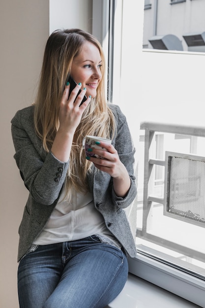 Bezpłatne zdjęcie kobieta z kubka mówiąc na telefon