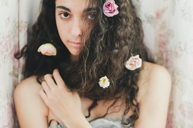 Kobieta z kwiatami w włosianej patrzeje kamerze