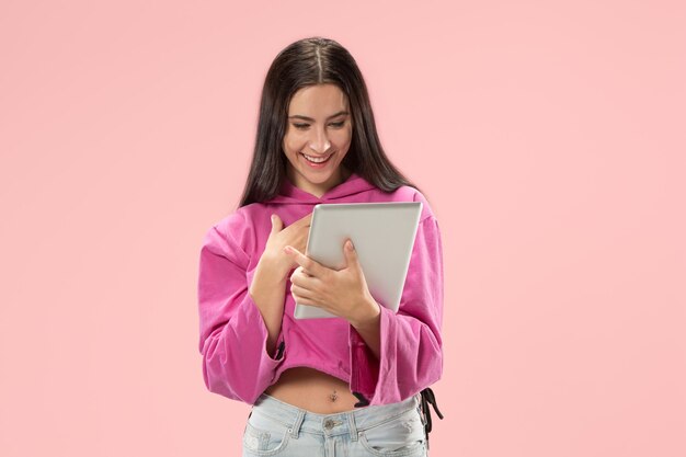 Kobieta z laptopem. Miłość do koncepcji komputera. Atrakcyjny portret kobiety do połowy długości z przodu, modna różowa ściana. Młoda emocjonalna ładna kobieta. Ludzkie emocje, wyraz twarzy