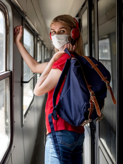 Bezpłatne zdjęcie kobieta z maską i hełmofonami w pociągu