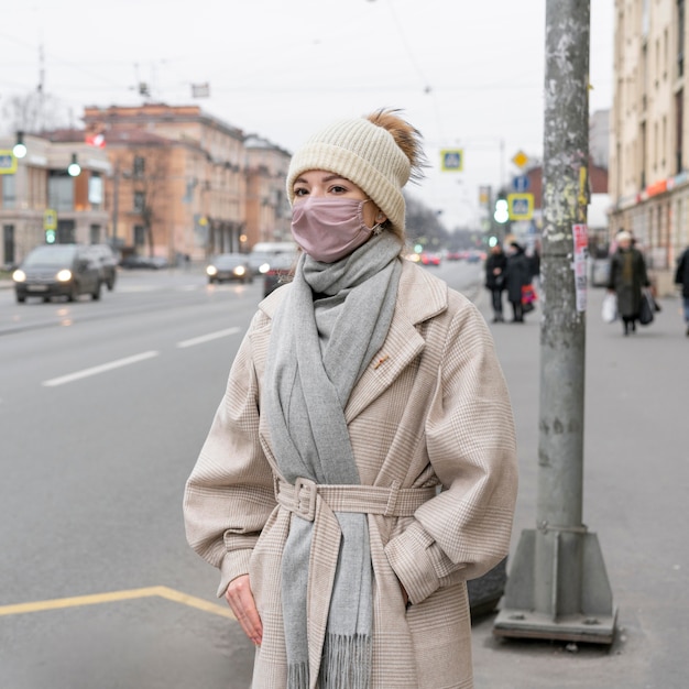 Bezpłatne zdjęcie kobieta z maską medyczną czeka na autobus w mieście