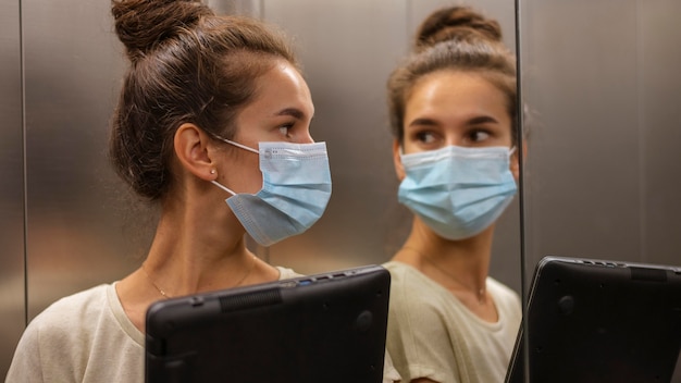 Bezpłatne zdjęcie kobieta z maską, patrząc na siebie przez lustro