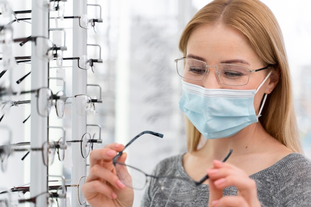 Kobieta z maską w sklepie przymierza okulary