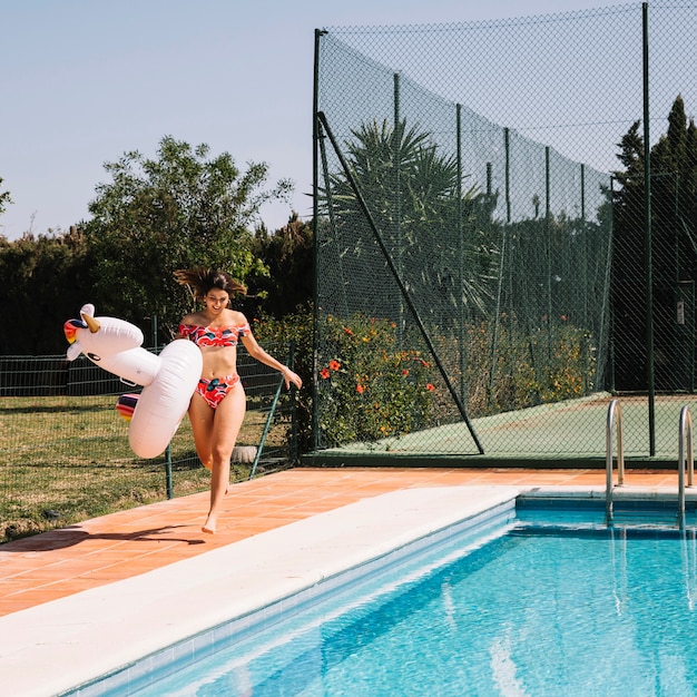 Kobieta z nadmuchiwaną jednorożec obok basenu