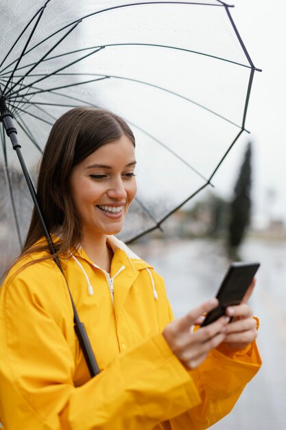 Kobieta z parasolem za pomocą telefonu komórkowego