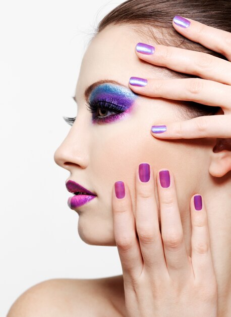 Kobieta z Piękną twarz i moda stylem makijażem i pięknem purpurowym manicure paznokci
