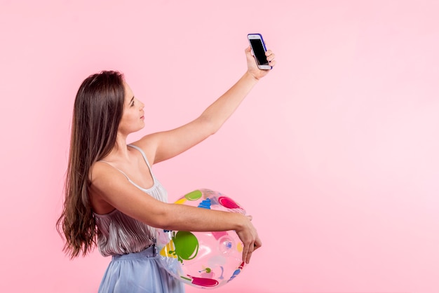 Kobieta z plażową piłką bierze selfie