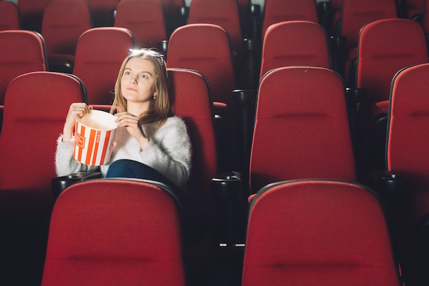 Bezpłatne zdjęcie kobieta z popcornem w kinowym audytorium