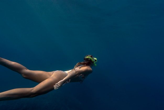 Bezpłatne zdjęcie kobieta z sprzęt do nurkowania pływanie w oceanie