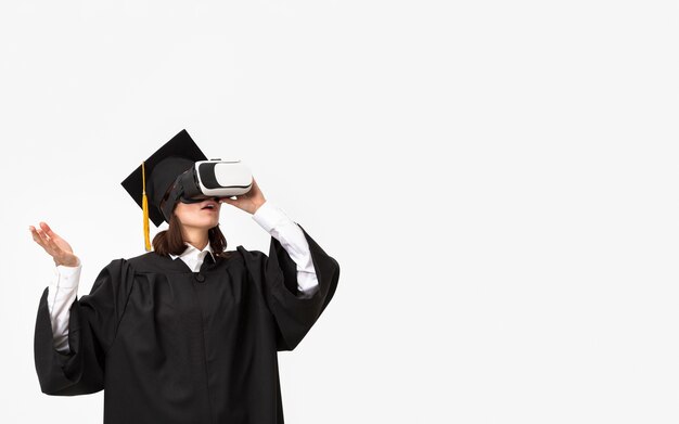 Kobieta z szlafrokiem i czapką ukończenia szkoły na sobie zestaw wirtualnej rzeczywistości