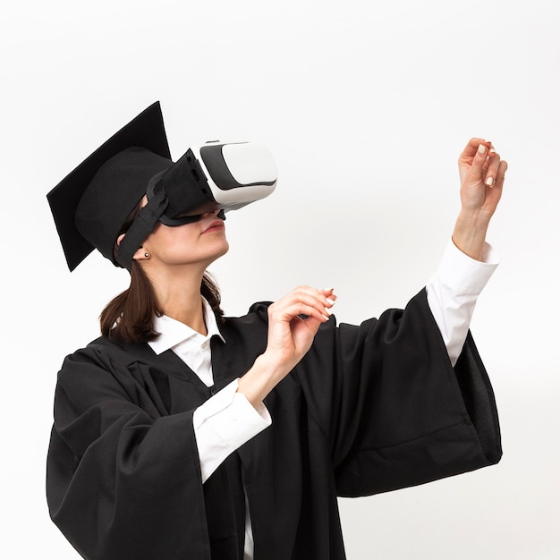 Bezpłatne zdjęcie kobieta z szlafrokiem i czapką ukończenia szkoły na sobie zestaw wirtualnej rzeczywistości