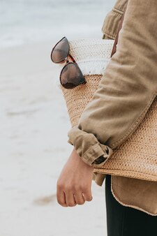Kobieta z torbą przeciwsłoneczną i okularami przeciwsłonecznymi na plaży, kopia przestrzeń, koncepcja wakacji i wakacji