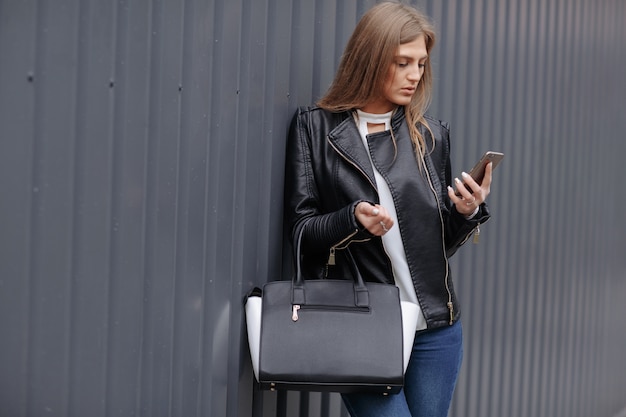 Kobieta z torebką patrząc na jej telefon komórkowy